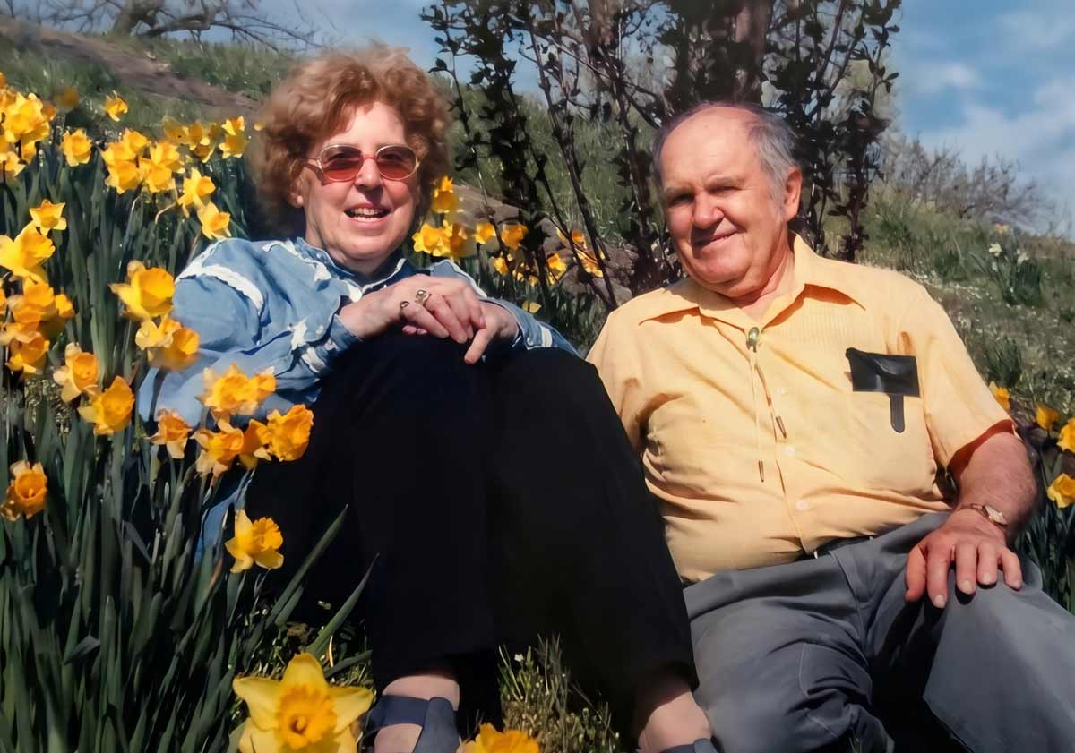 Frances and Richard sitting together on a hillside of daffodils.